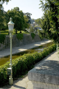 Street light by trees in garden against sky