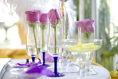 Close-up of wine glasses with pink roses on table