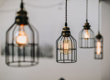 Lightbulbs protected by wire hang in front of a white wall inside