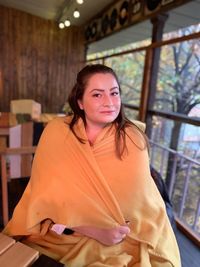 Portrait of beautiful woman sitting wrapped in blanket at home