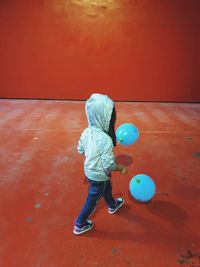 Rear view of girl playing with balloons