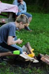 Side view of boy burning firewood at campsite