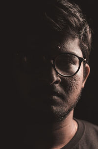 Close-up portrait of young man against black background