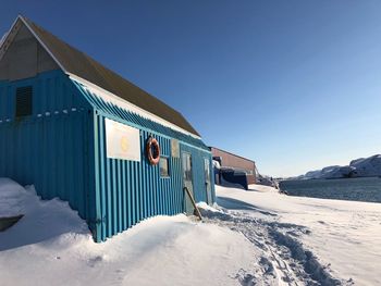 Snow covered building against blue sky