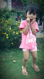 Full length of woman standing by pink flower on field