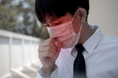 Close-up of teenage boy wearing mask coughing