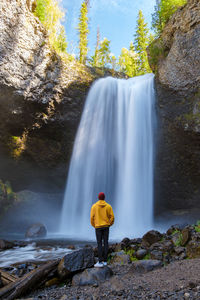 Rear view of woman standing against waterfall