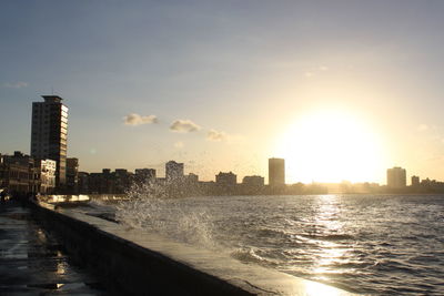 Sea by city against sky during sunset