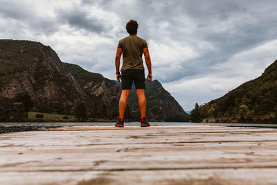 Rear view of man standing on wood against sky