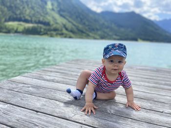 Portrait of young woman sitting on pier against mountain