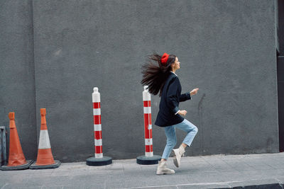 Full length of woman standing against wall