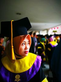 Woman wearing graduation gown while standing in university