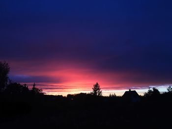 Silhouette trees on landscape against sky at sunset