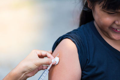 Cropped hand of doctor injecting girl