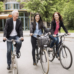 Happy business people riding bicycles on street