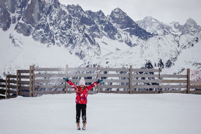 Child in alps with arms wide, joyous winter freedom.