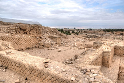 Old ruins on landscape against cloudy sky