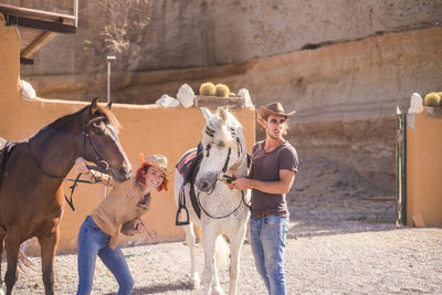 Friends with horses standing on footpath