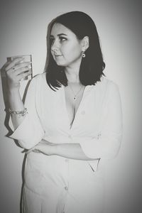 Portrait of young woman standing against white background