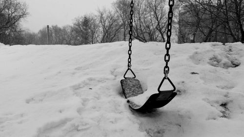 View of swing hanging on snow covered field