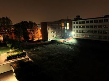 Illuminated buildings by canal against sky in city at night