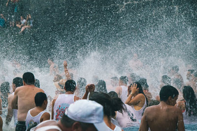 Rear view of people enjoying in sea