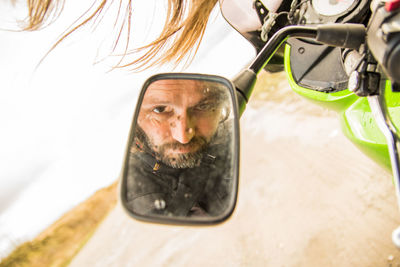 Portrait of man seen through side-view mirror