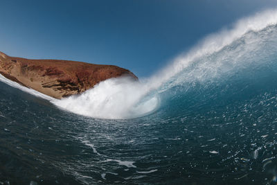 Scenic view of sea waves splashing against blue sky