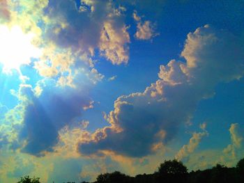 Low angle view of trees against cloudy sky