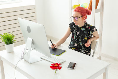 Woman using phone while sitting on table