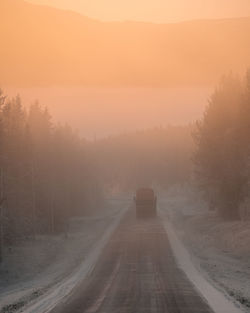 Road amidst trees against sky during winter