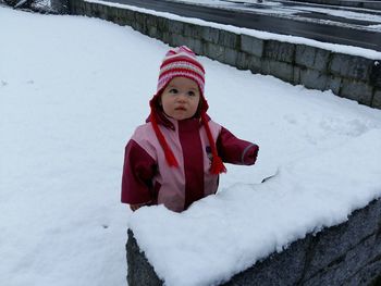 High angle view of cute girl looking away while standing on snow covered field