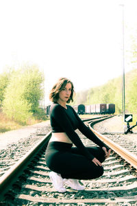 Portrait of woman sitting on railroad track