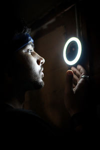 Portrait of man holding camera in darkroom