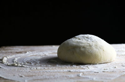 Close-up of bread on table against black background