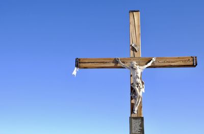 Low angle view of cross sign against blue sky