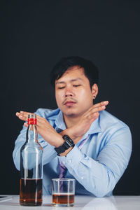 Young man sitting on table against black background