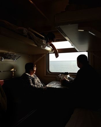 REAR VIEW OF MAN SITTING IN TRAIN