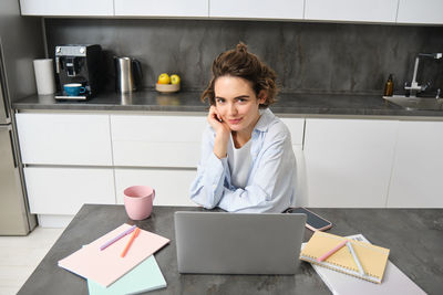 Young woman using laptop while sitting on table