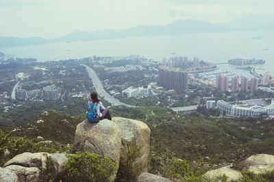 Man sitting in city against sky