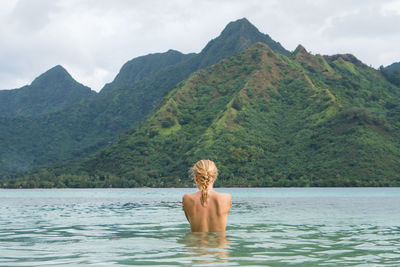 Rear view of woman against mountains in sea