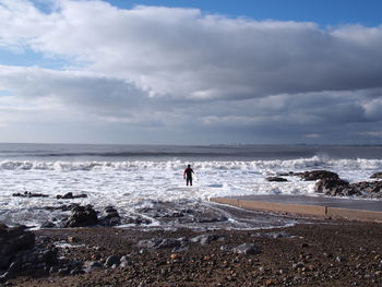 Man standing on beach and holding surfboard