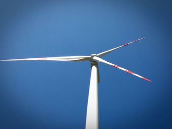 Low angle view of windmill against blue sky