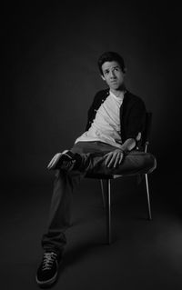 Fashion model sitting on chair against gray background