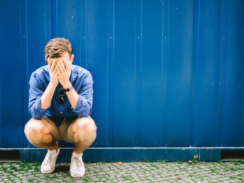 Full length of a young man sitting outdoors