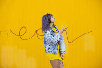 Woman standing against yellow wall