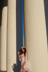 Young woman standing by column