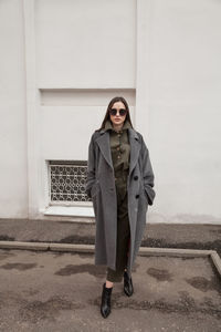 Female fashion model, posing for a full length photo, wearing green suit, urban fashion photography