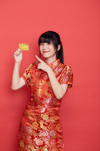 Portrait of a smiling young woman against red background