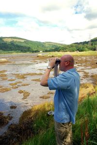 Full length of man photographing on field against sky